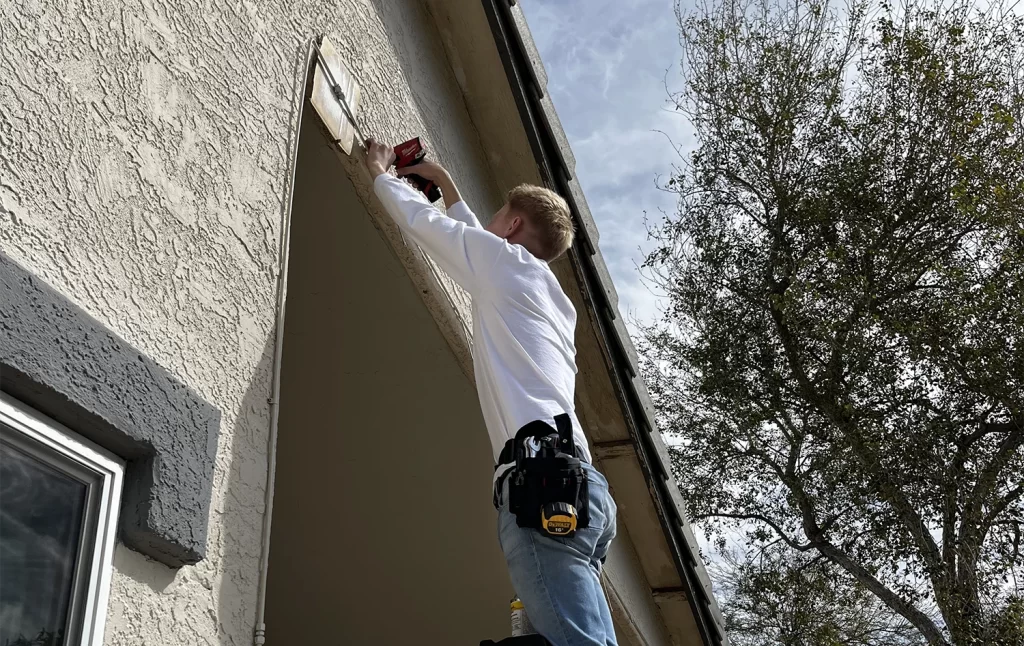 Another element mist team member on a ladder installing a patio misting system in an arizona backyard